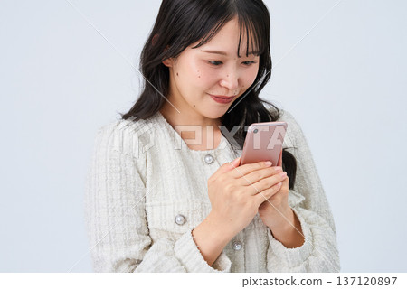 Smiling young woman holding a smartphone 137120897