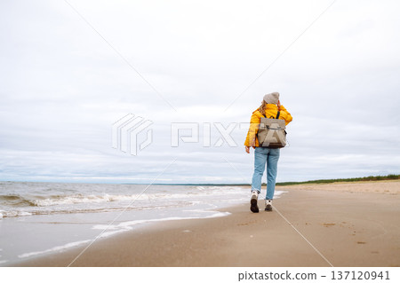 Woman tourist in a yellow jacket posing by the sea. Travelling, lifestyle, adventure. Woman tourist in a yellow jacket posing by the sea. Travelling, lifestyle, adventure. 137120941
