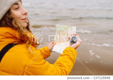 A young woman traveler with a compass and map, reading map looking for directions. Active lifestyle. A young woman traveler with a compass and map, reading map looking for directions. Active lifestyle. 137120946