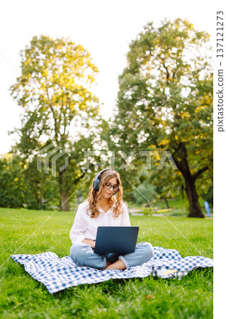 Portrait of woman sitting on green grass in park with legs crossed. Concept for education, business. Portrait of woman sitting on green grass in park with legs crossed. Concept for education, business. 137121273