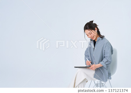 A young woman in casual clothes using a tablet PC 137121374
