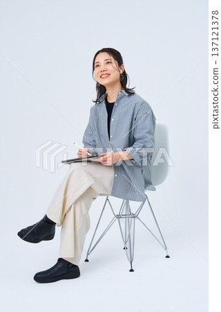 A young woman in casual clothes using a tablet PC A young woman in casual clothes using a tablet PC 137121378