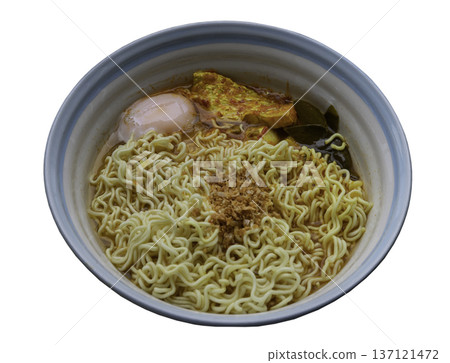 Instant noodles in spicy broth with sea bass and soft-boiled eggs topped with fried garlic. 137121472