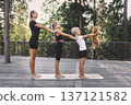 Happy family standing together on yoga mat outdoors in forest park. Mother and children practicing balance exercise with playful dog, healthy lifestyle, active recreation and wellness in nature 137121582