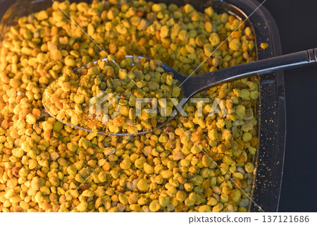 Close-up of natural bee pollen granules in vibrant yellow and orange tones, showcasing their organic texture. Close-up of natural bee pollen granules in vibrant yellow and orange tones, showcasing their organic texture. 137121686