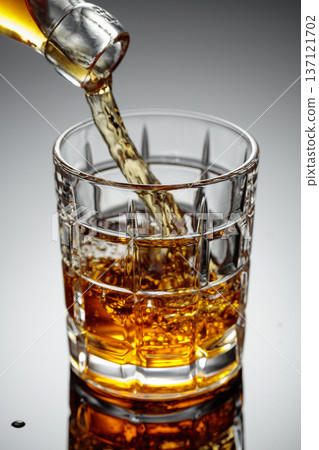 The amber-gold strong alcoholic beverage is poured into a glass. 137121702