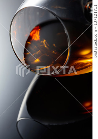 Glass of brandy on a black reflective background. Glass of brandy on a black reflective background. 137121711