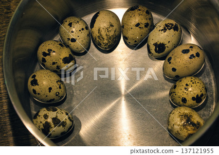 Top view of fresh speckled quail eggs arranged in a circle inside a metal bowl. Rustic food background showing organic farm produce, cooking ingredients, and healthy nutrition concept. Top view of fresh speckled quail eggs arranged in a circle inside a metal bowl. Rustic food background showing organic farm produce, cooking ingredients, and healthy nutrition concept. 137121955