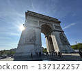 Low-angle view of the Arc de Triomphe in Paris shining under blue sky and sunlight 137122257