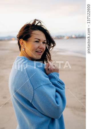 Woman Smiling on Beach in Blue Sweater 137122600