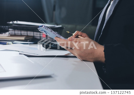 Auditors collaborating in modern office, analyzing financial documents and using calculator with a laptop displaying charts. Audit and taxes in business 137122745