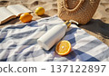 Beach picnic items including sunscreen bottle, open book, and straw bag on sand. Summer vacation relaxation concept. 137122897