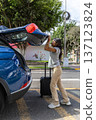 A teenager is getting ready to leave her car and is pulling out a suitcase 137123824