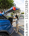 A teenager is opening the trunk of a blue car 137123829