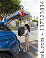 A teenager is opening the trunk of a blue car 137123834