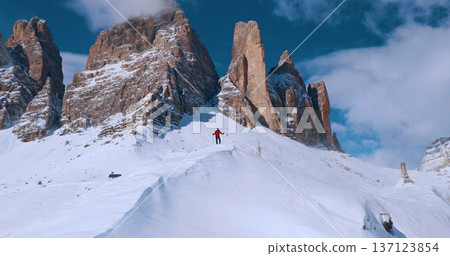 Ski mountaineer crossing a snowy ridge in the Dolomites with dramatic alpine peaks and blue sky in the background, capturing winter adventure and breathtaking mountain landscape. Ski mountaineer crossing a snowy ridge in the Dolomites with dramatic alpine peaks and blue sky in the background, capturing winter adventure and breathtaking mountain landscape. 137123854