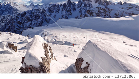 Ski mountaineer crossing a snowy ridge in the Dolomites with dramatic alpine peaks and blue sky in the background, capturing winter adventure and breathtaking mountain landscape. Ski mountaineer crossing a snowy ridge in the Dolomites with dramatic alpine peaks and blue sky in the background, capturing winter adventure and breathtaking mountain landscape. 137123865