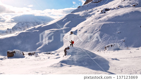 Ski mountaineer standing on a snowy rock in the Dolomites with wind blowing snow across alpine slopes, capturing winter adventure, solitude and dramatic mountain landscape. Ski mountaineer standing on a snowy rock in the Dolomites with wind blowing snow across alpine slopes, capturing winter adventure, solitude and dramatic mountain landscape. 137123869