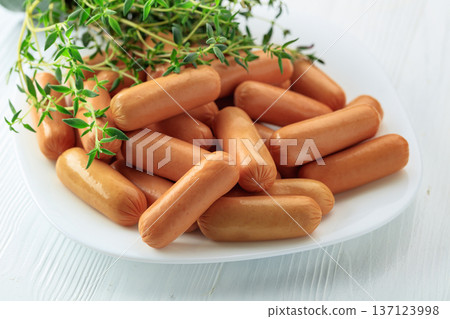 Boiled sausages with thyme on a white wooden table. Boiled sausages with thyme on a white wooden table. 137123998