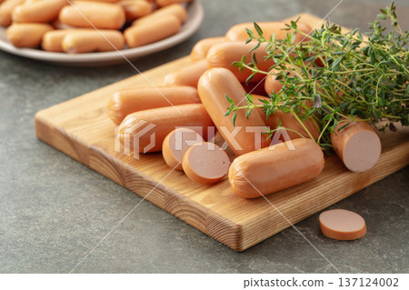 Small boiled sausages with thyme on a cutting board. Small boiled sausages with thyme on a cutting board. 137124002