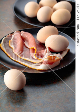 Smoked pork bacon with eggs on a black plate. Smoked pork bacon with eggs on a black plate. 137124014