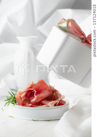 Prosciutto with rosemary in gift box on a white wooden table. 137124018