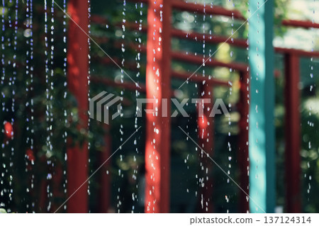 Abstract view of falling water drops with colorful blurred background, creating a fresh and calming atmosphere. Ideal for themes of rain, fountain water, relaxation, and nature-inspired texture backgr Abstract view of falling water drops with colorful blurred background, creating a fresh and calming atmosphere. Ideal for themes of rain, fountain water, relaxation, and nature-inspired texture backgr 137124314