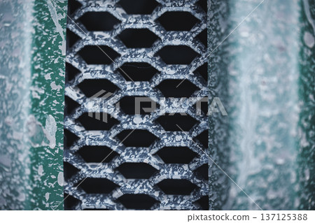 Weathered Metal Vent Grid Macro Texture Close-up of old painted metal grille with peeling paint and corrosion forming abstract industrial pattern 137125388