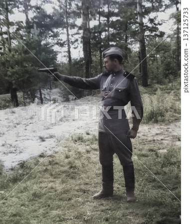 A vintage portrait of a young lieutenant during marksmanship training. The soldier holds a gun. Retro photo from 1952. A vintage portrait of a young lieutenant during marksmanship training. The soldier holds a gun. Retro photo from 1952. 137125733
