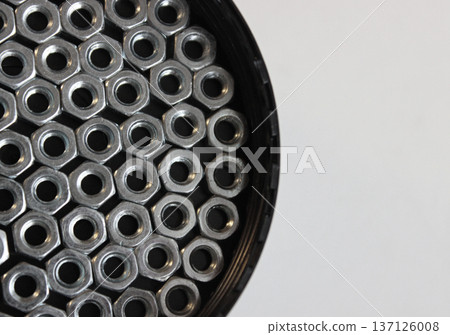 Heavy Hex Nuts Completely Cover The Bottom Of Round Screw Box On A White Surface 137126008