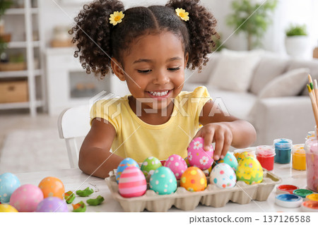 Smiling african american girl decorating Easter eggs. Creative child making craft for holiday. Happy kid activity and spring event for family. 137126588