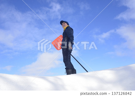 An elderly man living in a snowy country is clearing snow An elderly man living in a snowy country is clearing snow 137126842