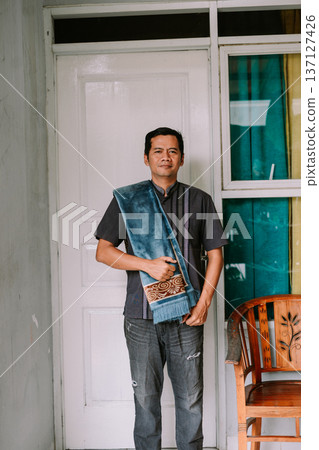 Asian Man Holding Prayer Mat at Home Entrance Asian Man Holding Prayer Mat at Home Entrance 137127426