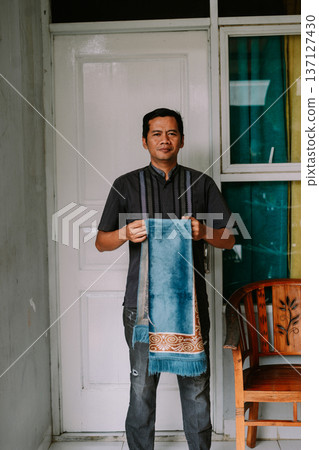 Muslim man holding a blue prayer mat for prayer Muslim man holding a blue prayer mat for prayer 137127430
