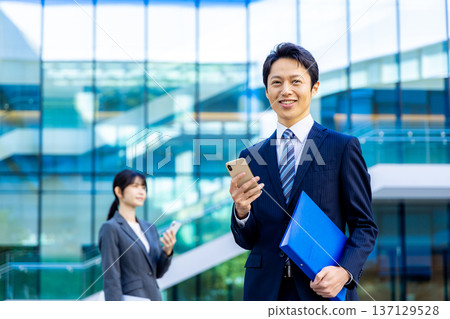 Young businessman, skyscraper, smartphone, business image Young businessman, skyscraper, smartphone, business image 137129528