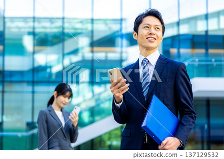 Young businessman, skyscraper, smartphone, business image Young businessman, skyscraper, smartphone, business image 137129532