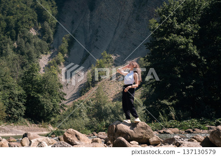 Young Woman Standing on Rock by Mountain River in Summer Nature 137130579