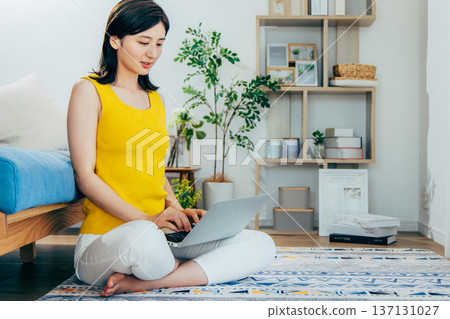 A woman watching a computer in a room 137131027