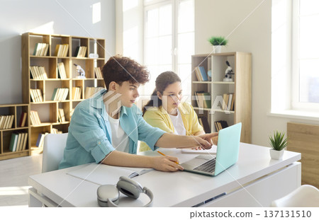 Teen students pointing at laptop screen in library classroom during group study 137131510