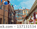Festive bunting and lanterns decorate a narrow street for summer festival in June San Juan 137131534