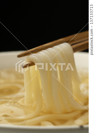 Pick up cold udon noodles with chopsticks 137133713