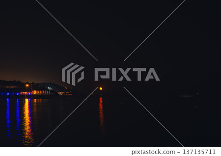 Moonlight Over Sea Waves Full Moon Glow ocean waves on sandy beach at night wooden pier. The moon illuminates water surface. Concept of beach vacation slowing down on seacoast 137135711