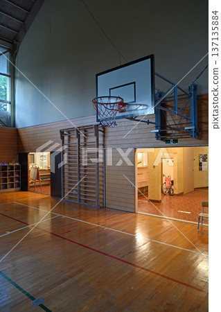 The wooden walls and basketball hoops of an elementary school gymnasium give off a nostalgic Showa-era vibe. 137135884