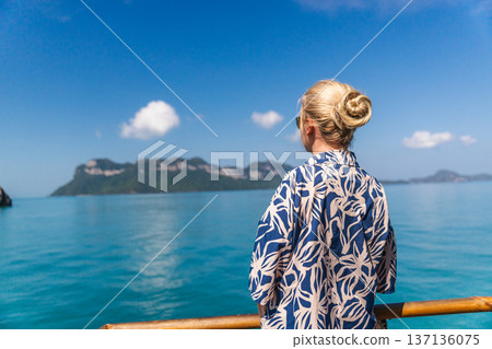 Middle-aged woman standing on cruise ship deck and looking at tropical islands in Ang Thong Marine Park Thailand during sea journey Middle-aged woman standing on cruise ship deck and looking at tropical islands in Ang Thong Marine Park Thailand during sea journey 137136075
