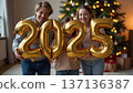 The father and children hold shimmering golden and silver balloons spelling 2025. 137136387
