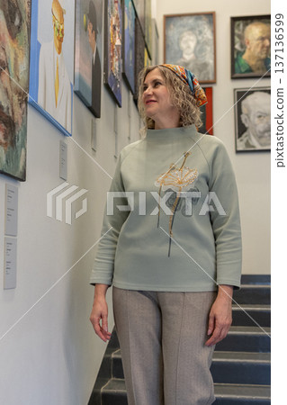Woman appreciating contemporary art inside modern museum space and while viewing framed paintings. Woman appreciating contemporary art inside modern museum space and while viewing framed paintings. 137136599