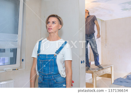 Workers make repairs in new apartment. Woman and man plaster walls and ceilings. High quality photo Workers make repairs in new apartment. Woman and man plaster walls and ceilings. High quality photo 137136634