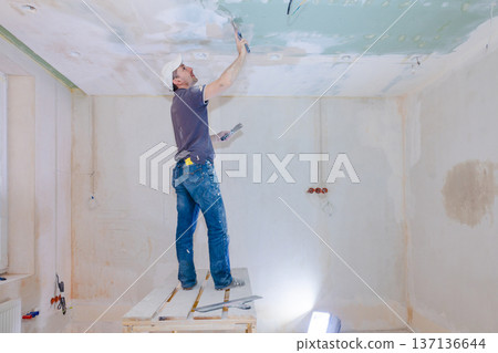 Worker make repairs in new apartment. Man plaster walls and ceilings. High quality photo Worker make repairs in new apartment. Man plaster walls and ceilings. High quality photo 137136644
