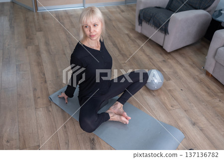 Core Activation. Indoor workout with woman performing controlled abdominal exercise in cozy home interior. Core Activation. Indoor workout with woman performing controlled abdominal exercise in cozy home interior. 137136782