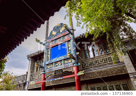 Ornate traditional Chinese signboard with blue panel, carved details and red columns on traditional building facade in Gubei Town China. 137136903